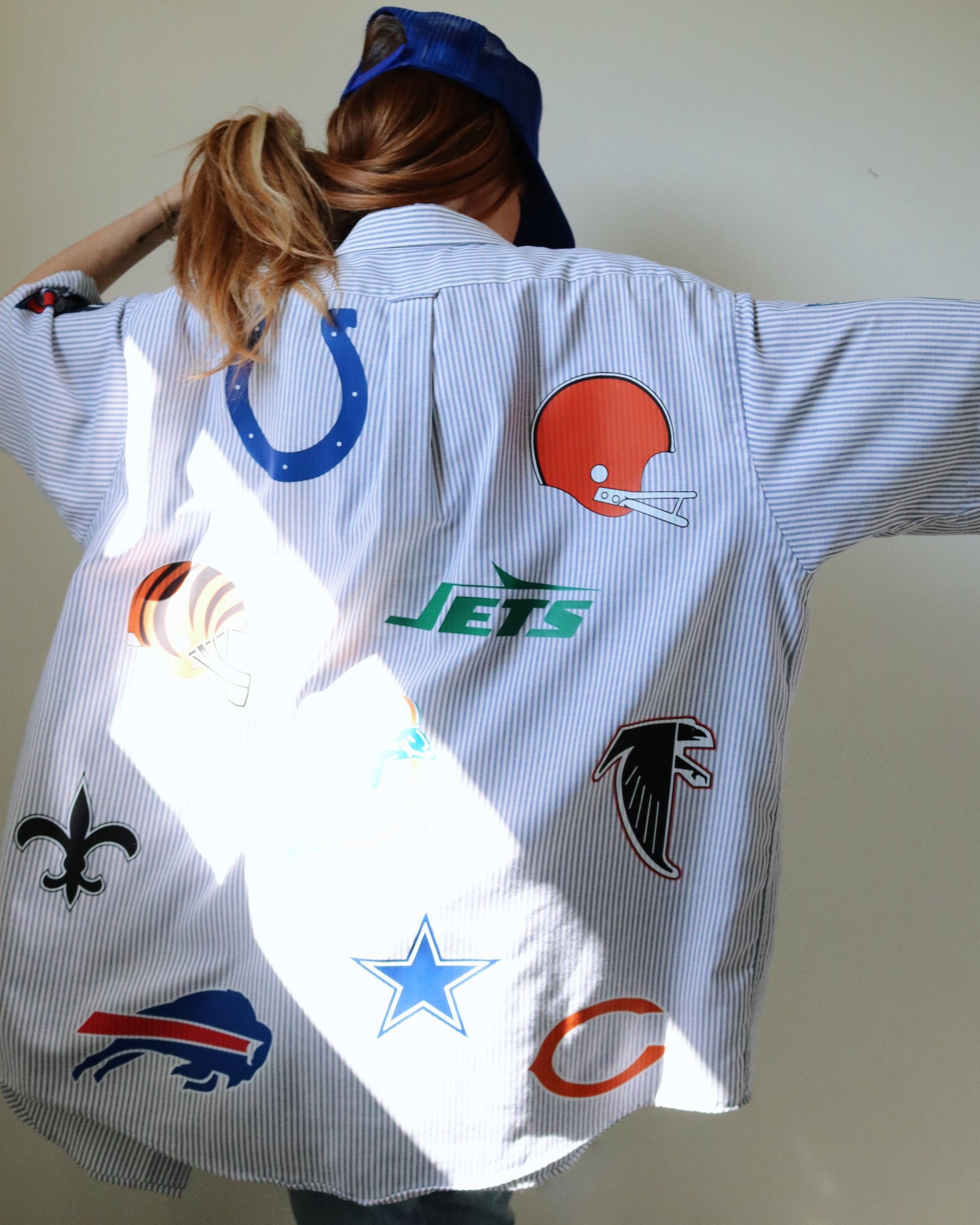 Person wearing a shirt with various sports team logos on a plain background Shirt for game day shirt