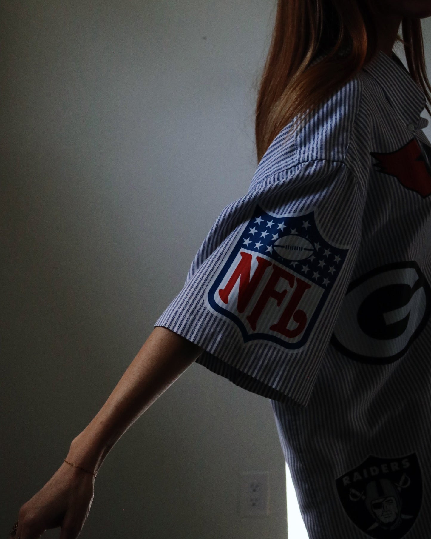 Person wearing a shirt with NFL logo in a dimly lit room