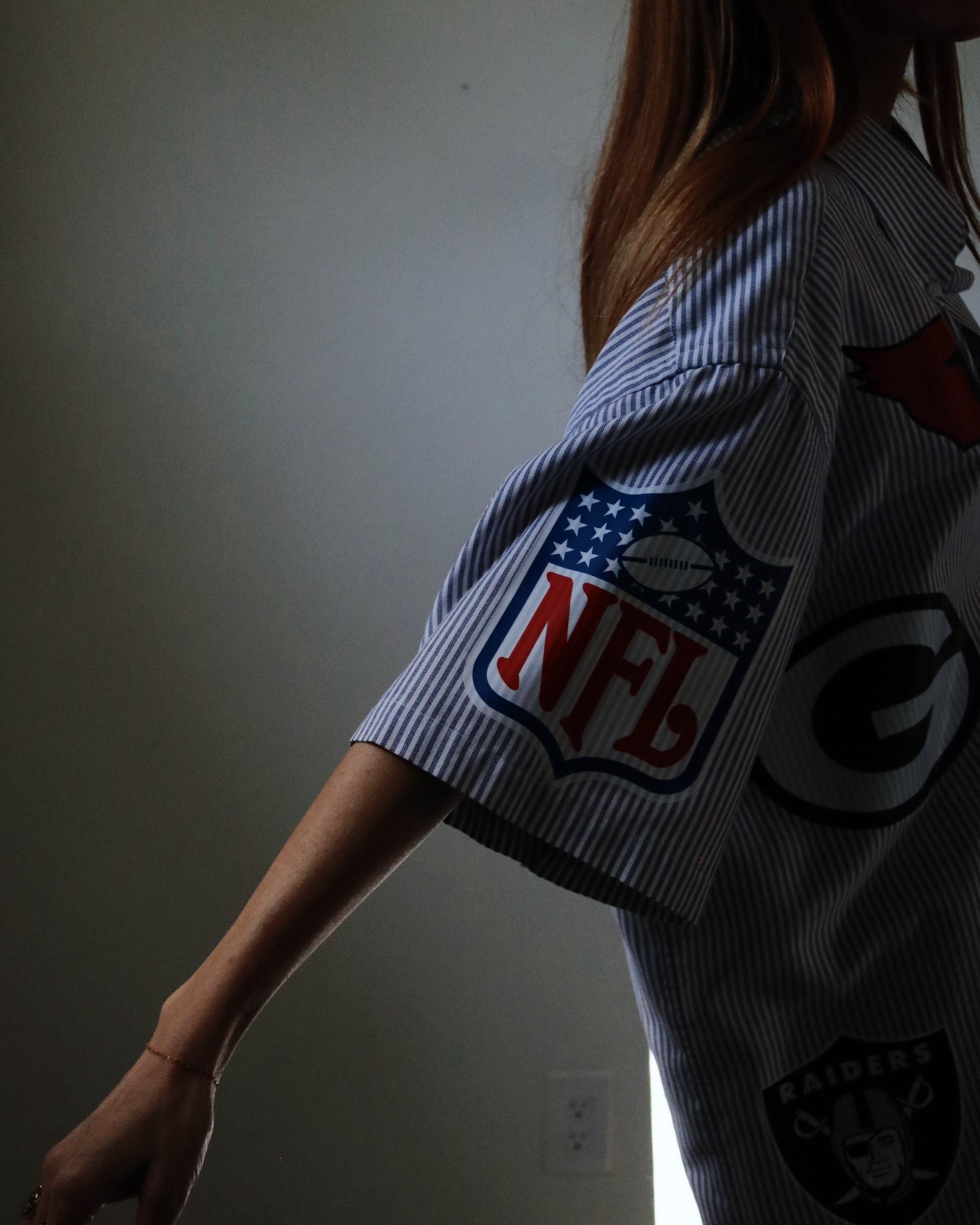 Person wearing a shirt with NFL logo in a dimly lit room