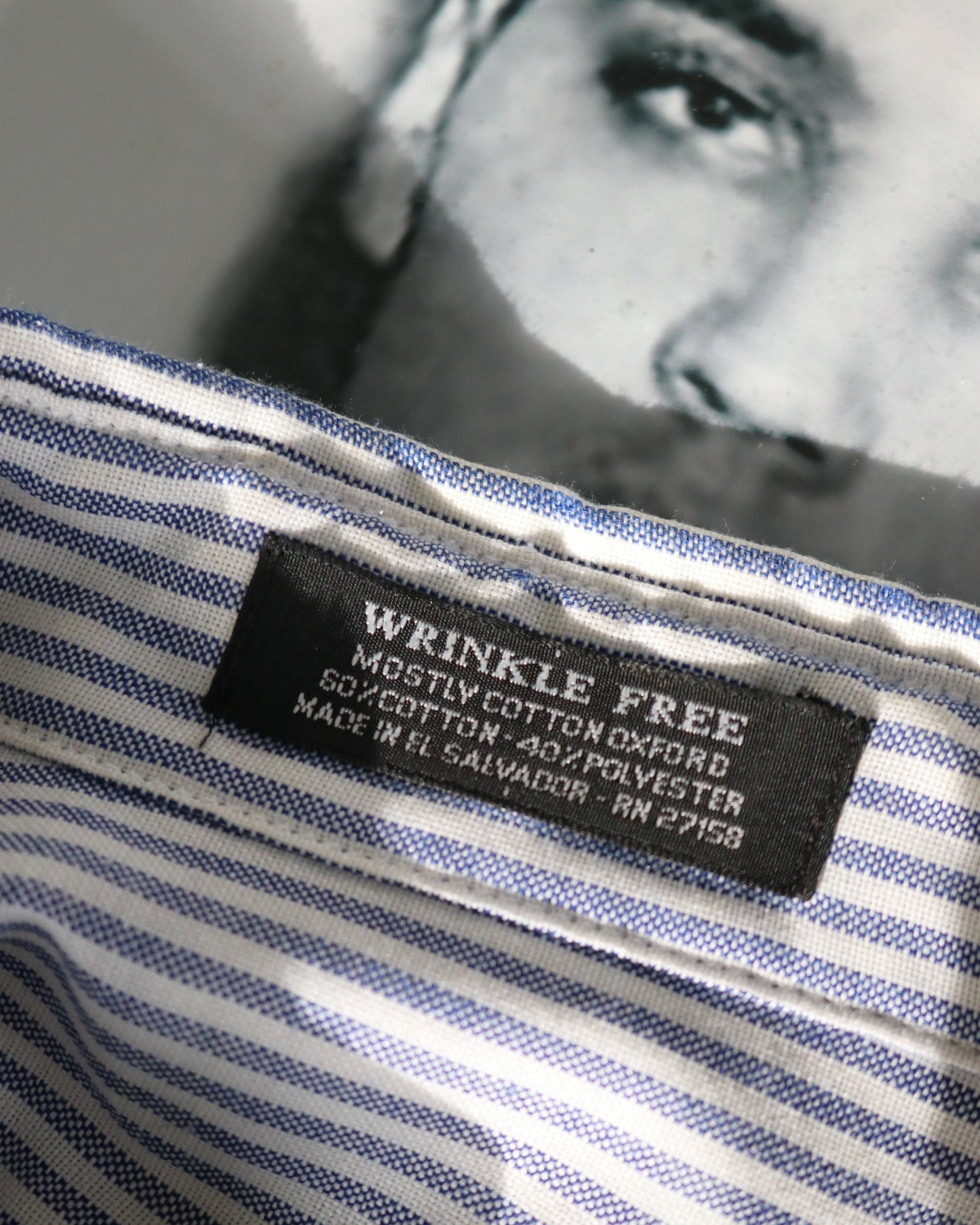 Close-up of a wrinkle-free label on a striped shirt with a blurred portrait in the background.