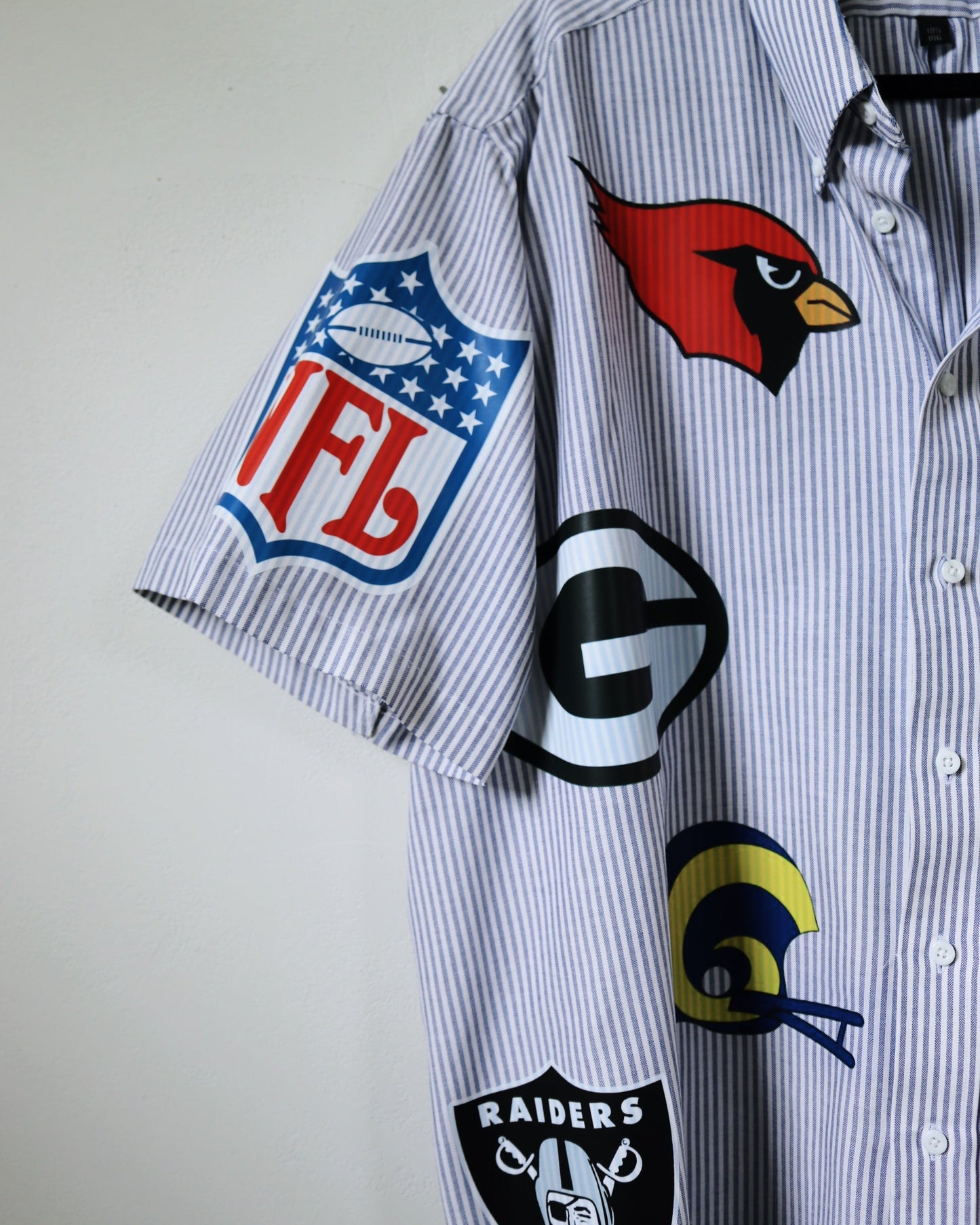Striped shirt with various sports team logos on a plain background