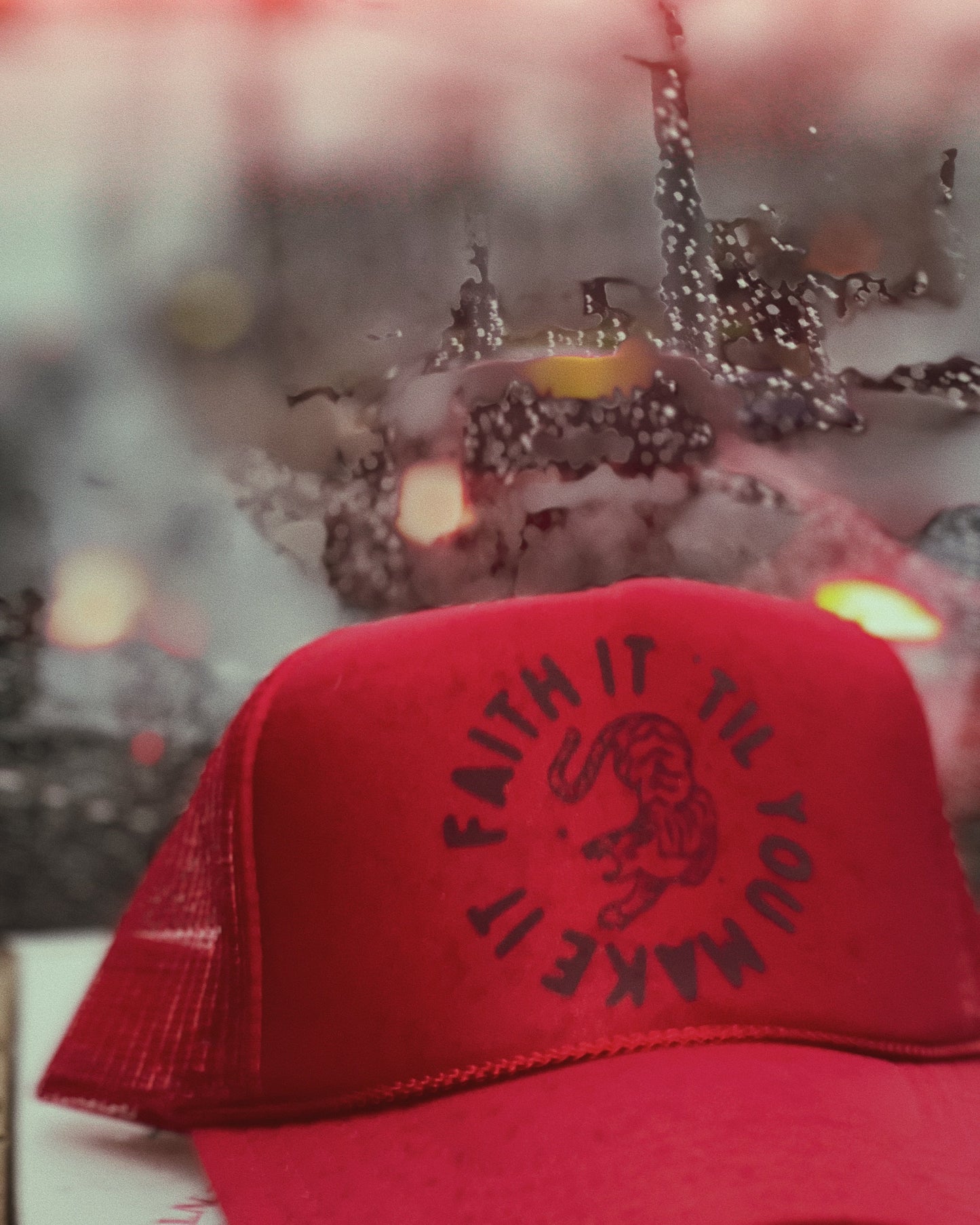 Red cap with 'Faith It To Your Maker' text and snake design on a blurred background