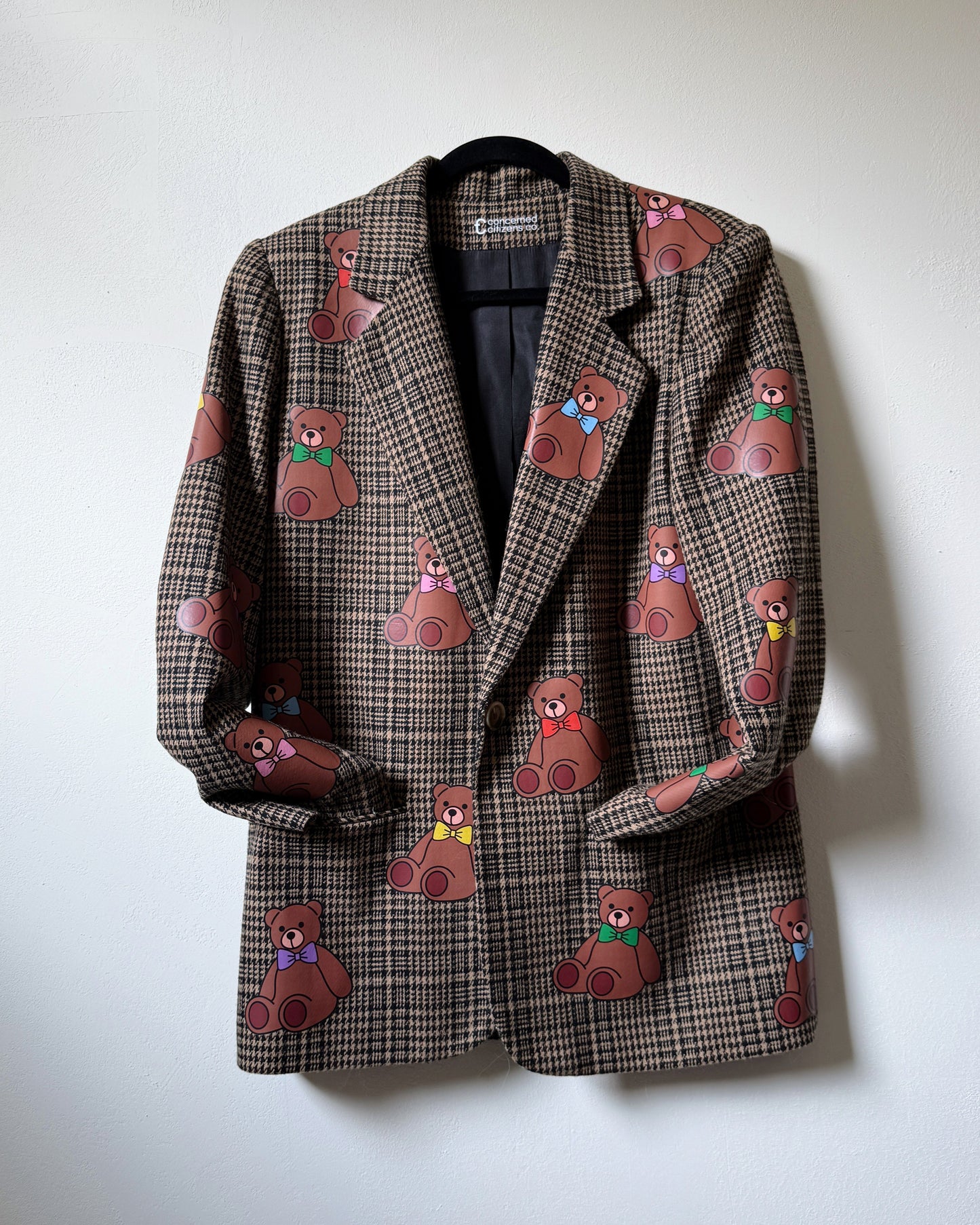 A tweed blazer with a pattern of teddy bears in various colors.