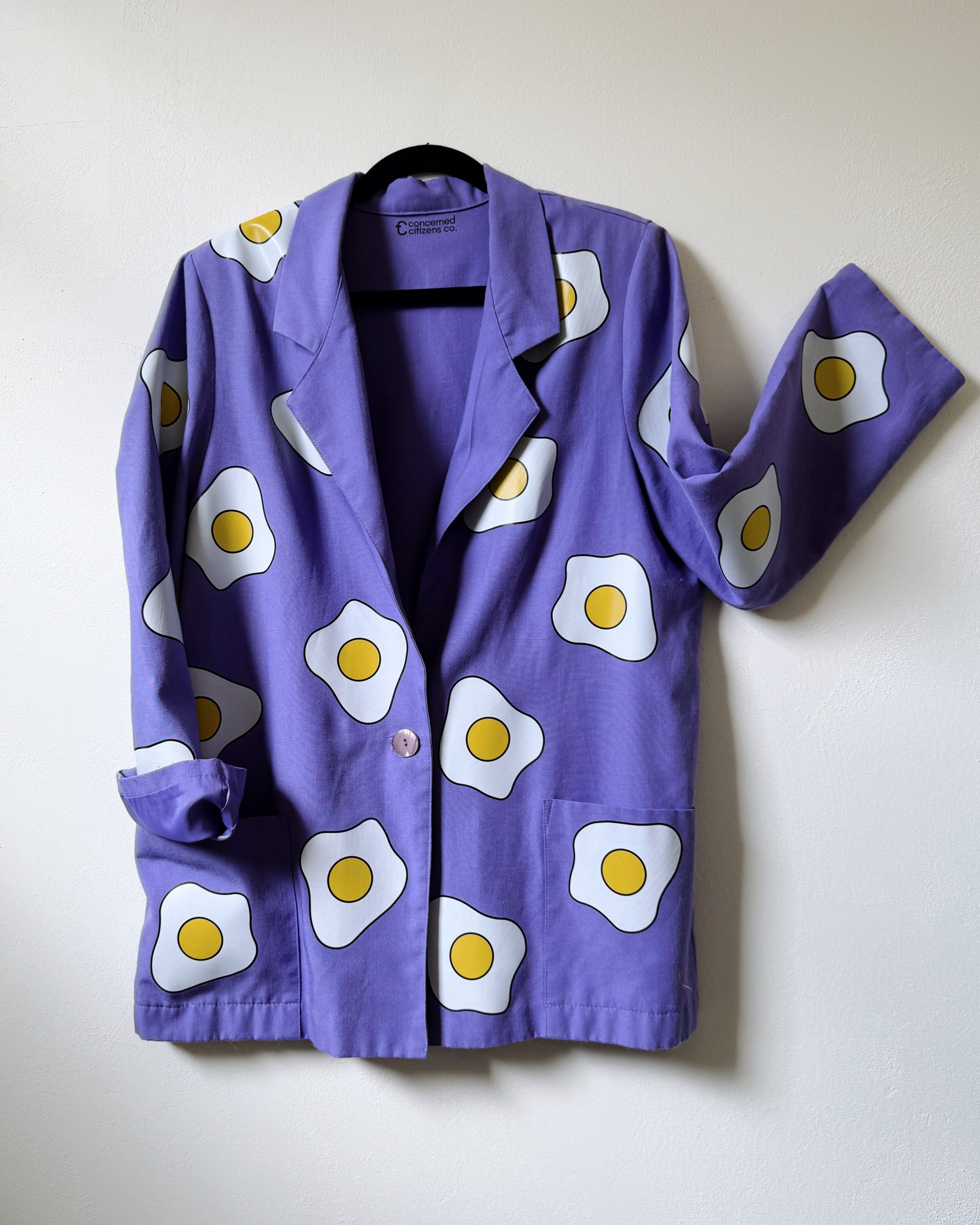 A purple blazer with a pattern of eggs displayed on it, against a plain background.