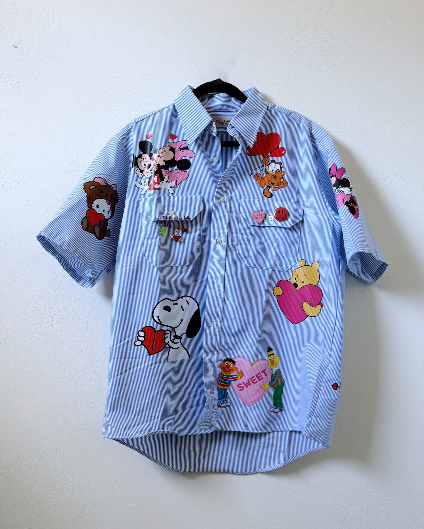 A light blue button-up shirt with various cartoon character appliques.