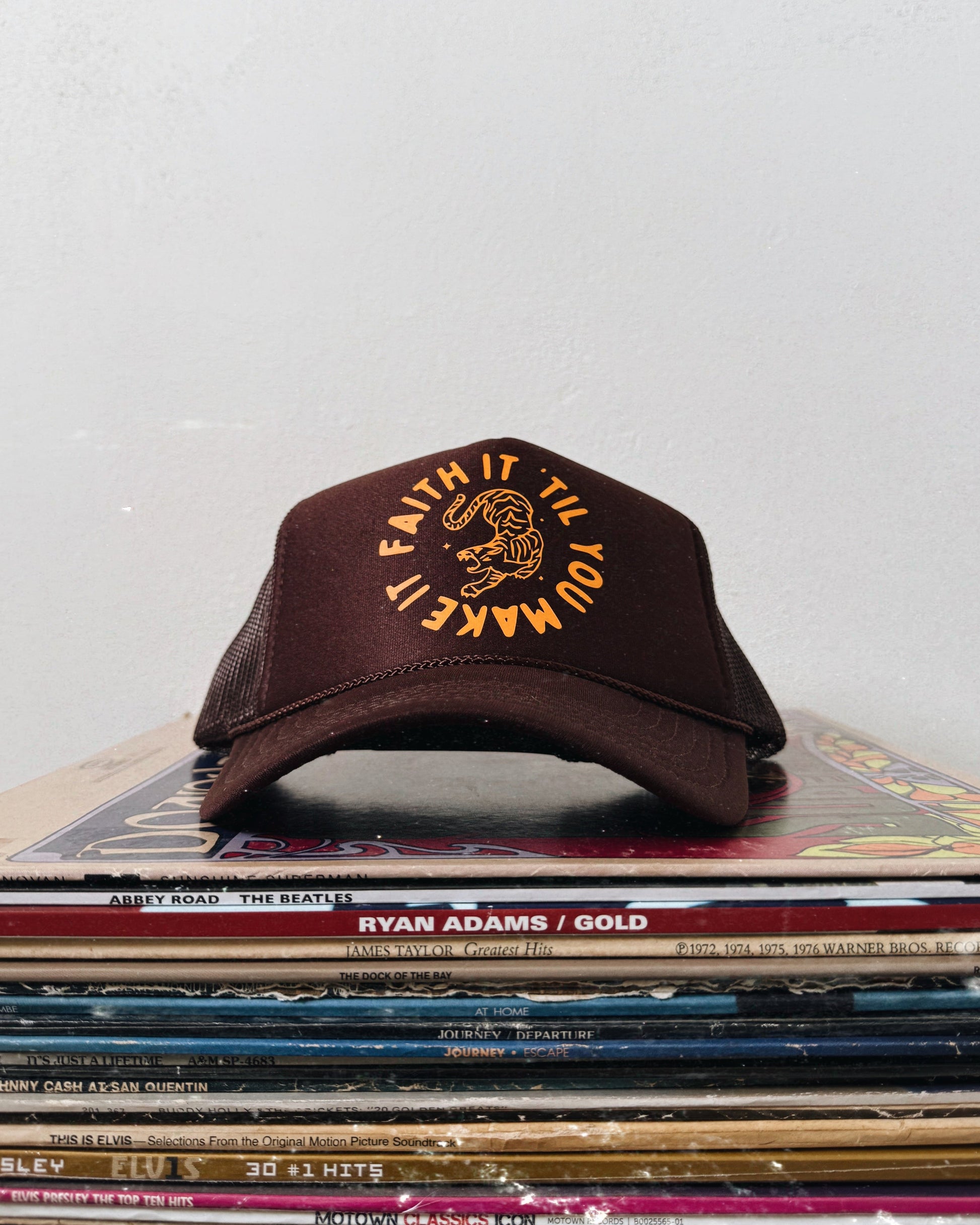 Brown cap with yellow text on a stack of vinyl records