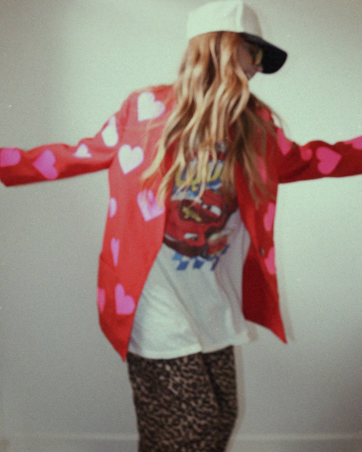 Model wearing upcycled red blazer with neon pink hearts, side/back view, showing oversized fit and bold design