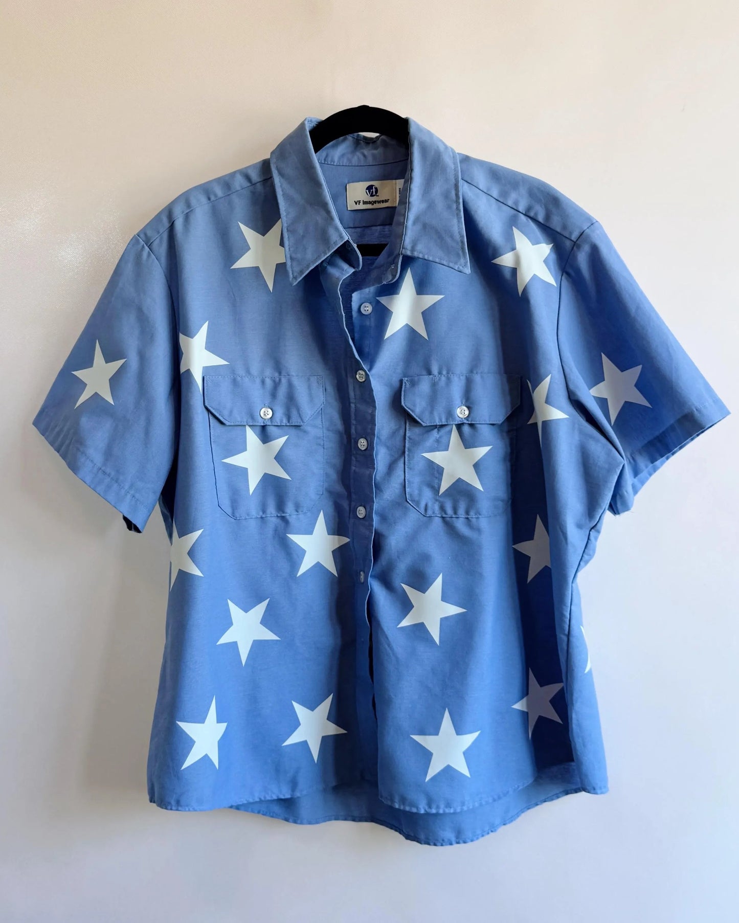 Blue shirt with white star patterns on a plain background Upcycled blue shirt with cute white stars shirt