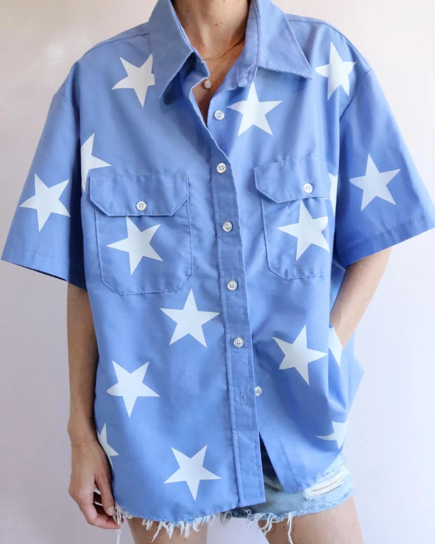 Blue shirt with white star patterns worn by a person on a plain background Oversized Blue Button up with white star designs