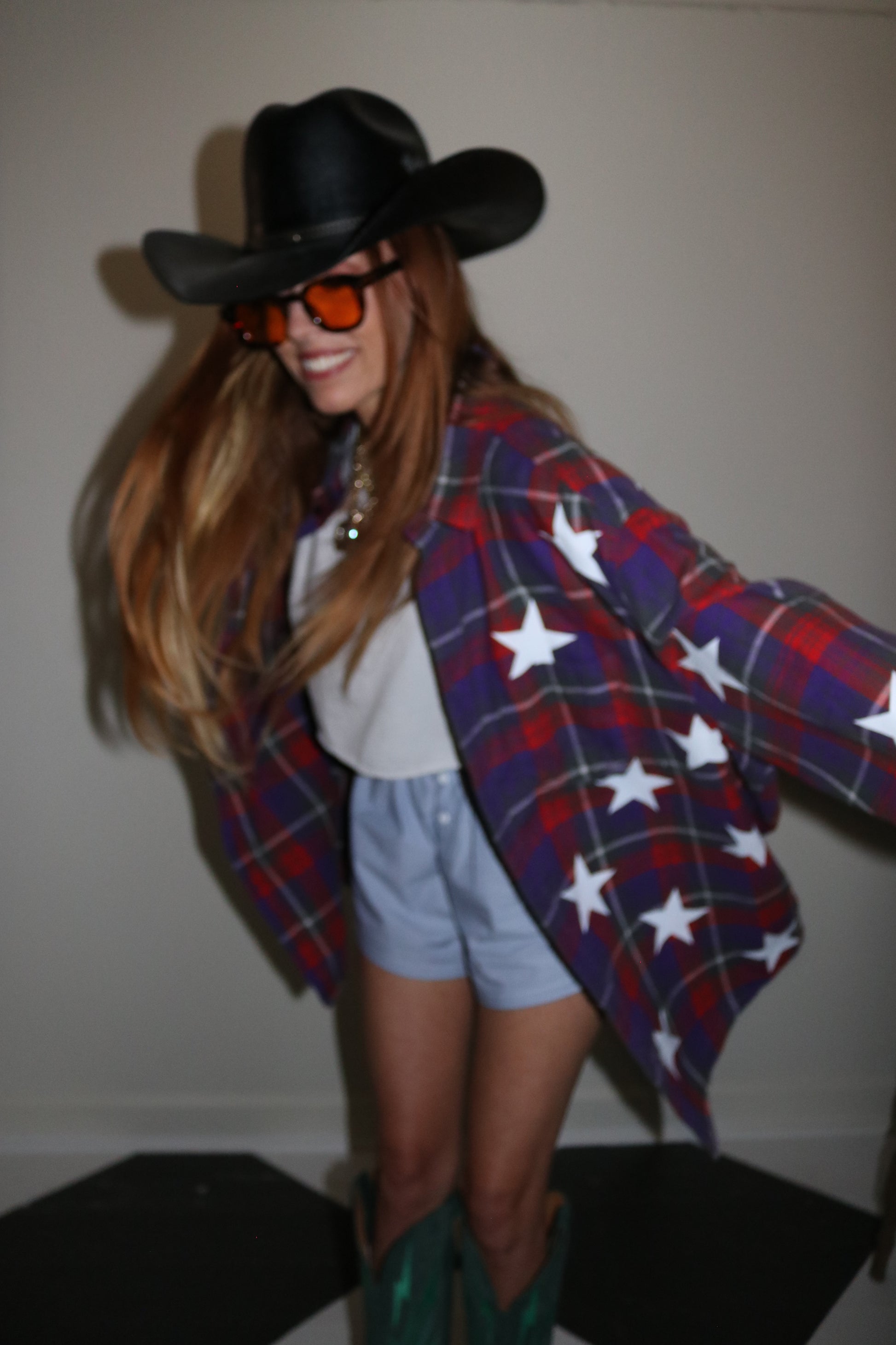 Person wearing a plaid outfit with star patterns and a black hat.