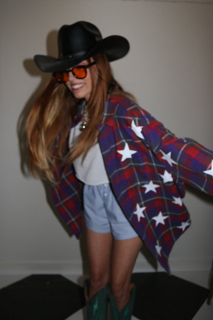 Person wearing a plaid outfit with star patterns and a black hat.