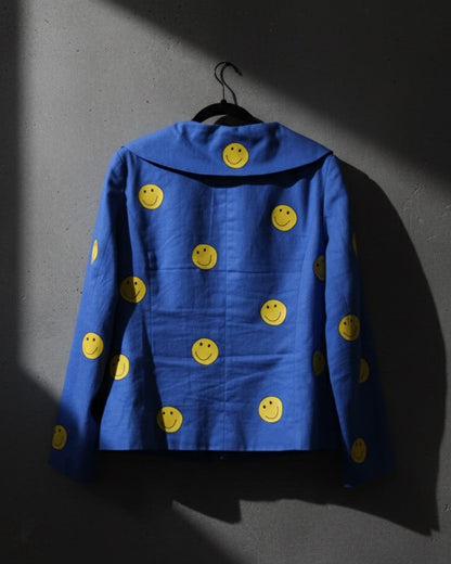 Blue jacket with yellow smiley face patterns on a dark background