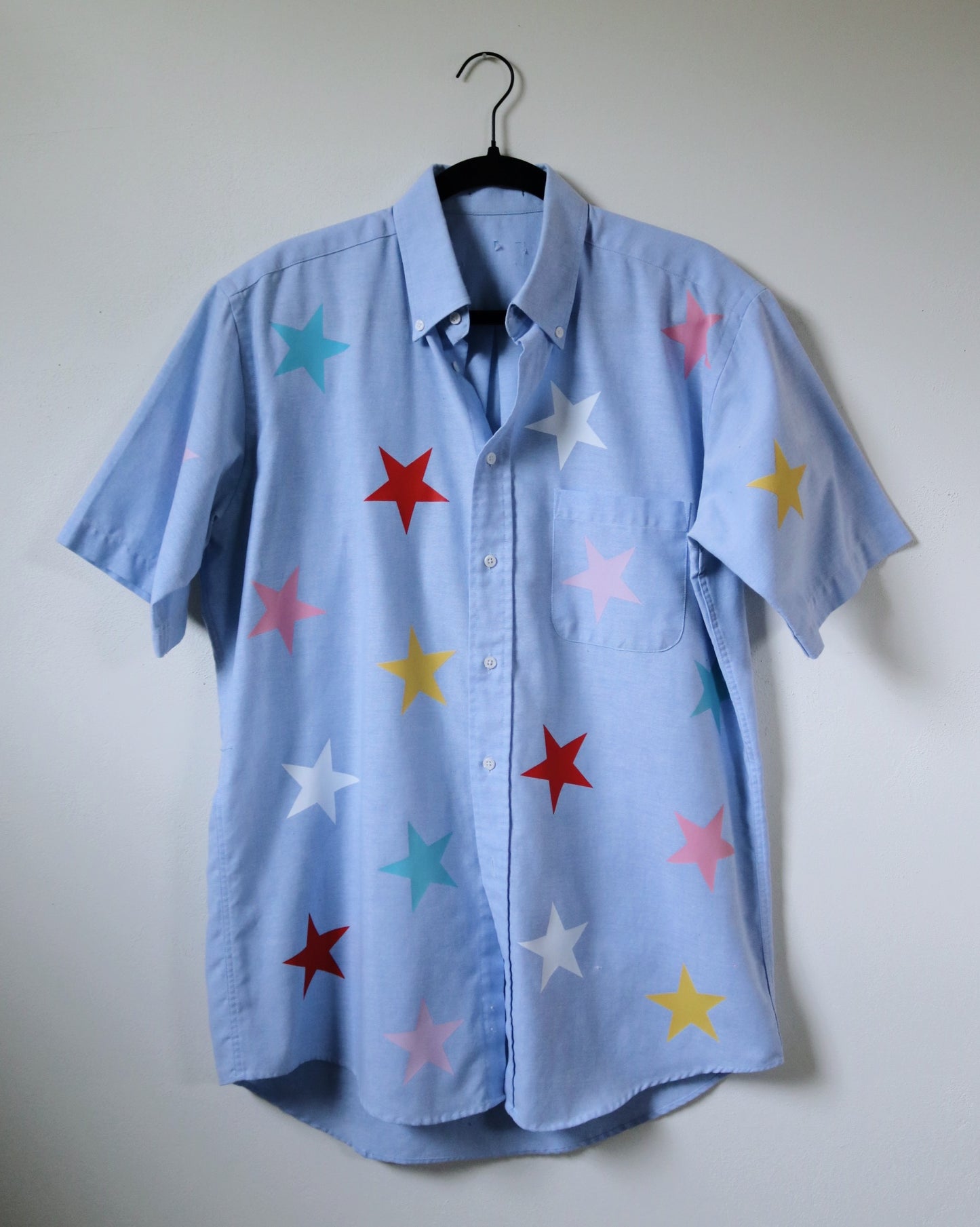 Light blue shirt with colorful star patterns on a white background