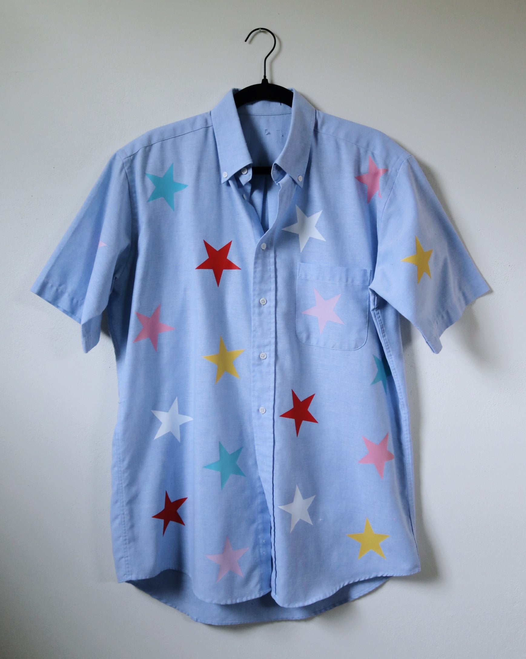 Light blue shirt with colorful star patterns on a white background