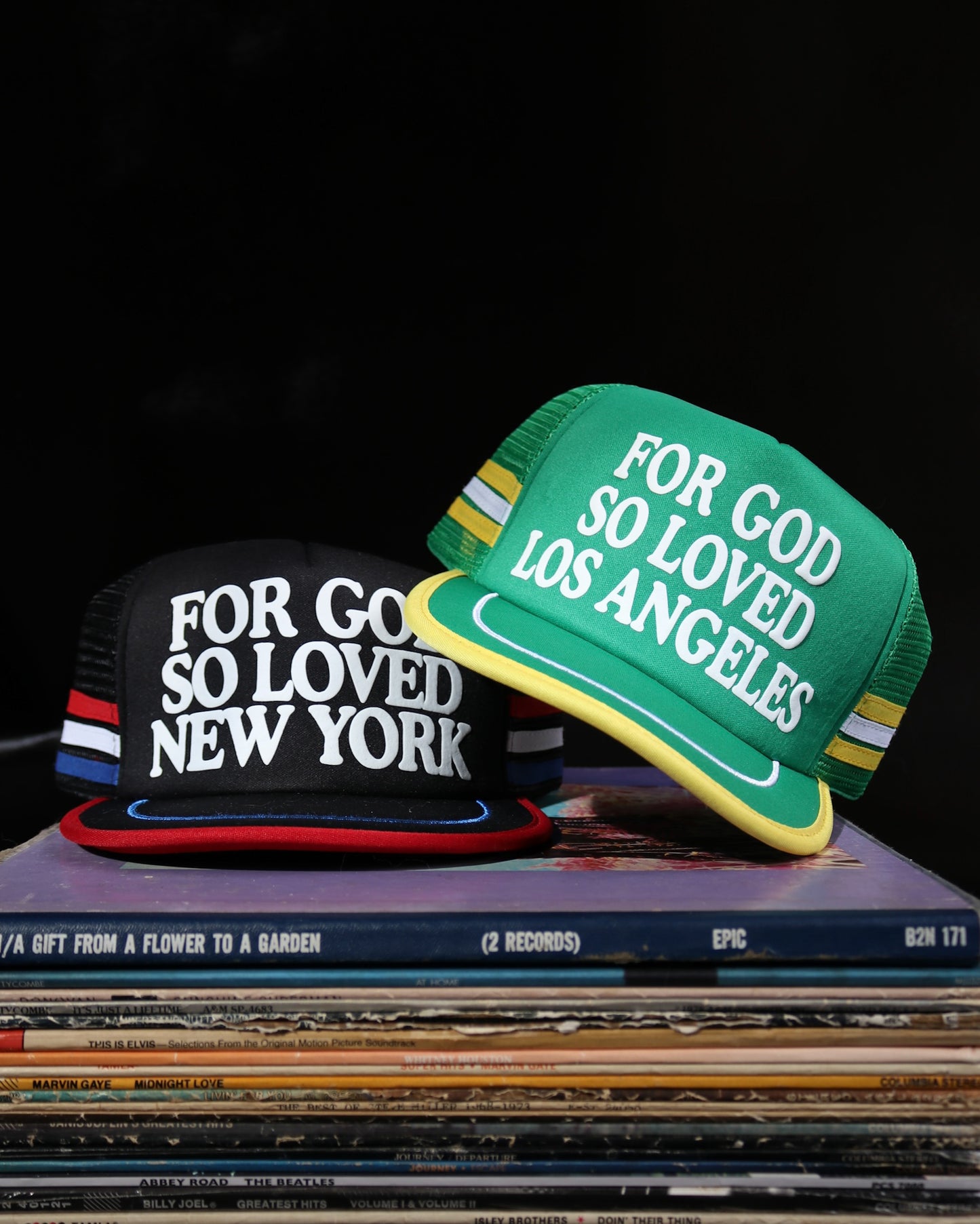 Two hats with text on a stack of vinyl records against a dark background
