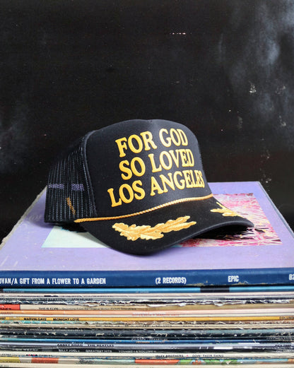 Black cap with 'For God So Loved Los Angeles' text on a stack of records