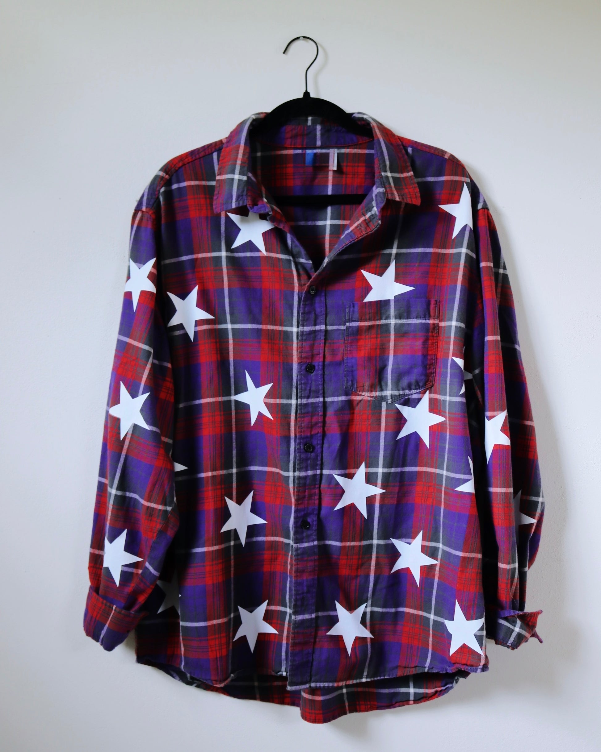 Plaid shirt with white star pattern on a hanger against a white background