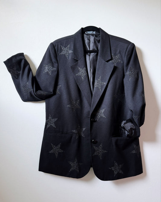 A black blazer with glitter star designs spread out on a flat surface.