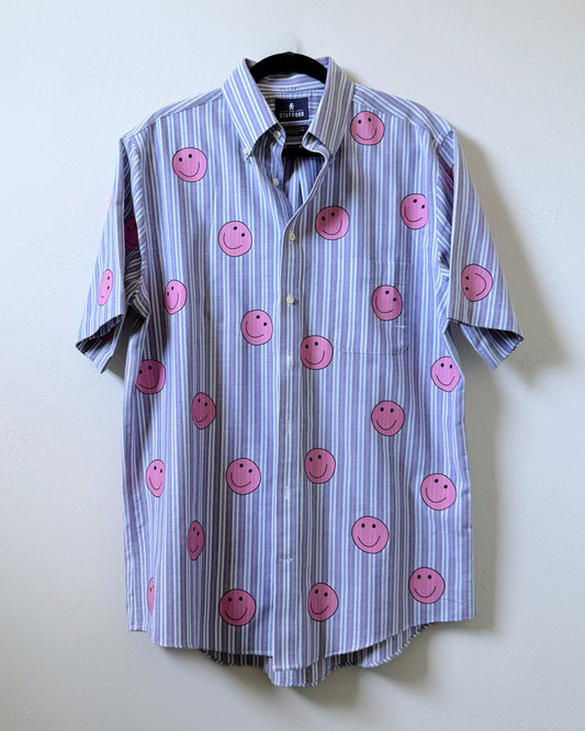 A button-up shirt with a striped pattern featuring pink smiley face designs on the front.