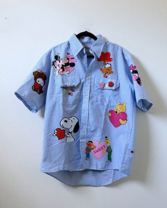 A light blue button-up shirt with various cartoon character appliques.